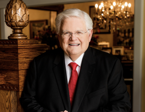 Pastor-Hagee-smiling-in-a-black-suit-with-a-red-tie-e1687295174730.png
